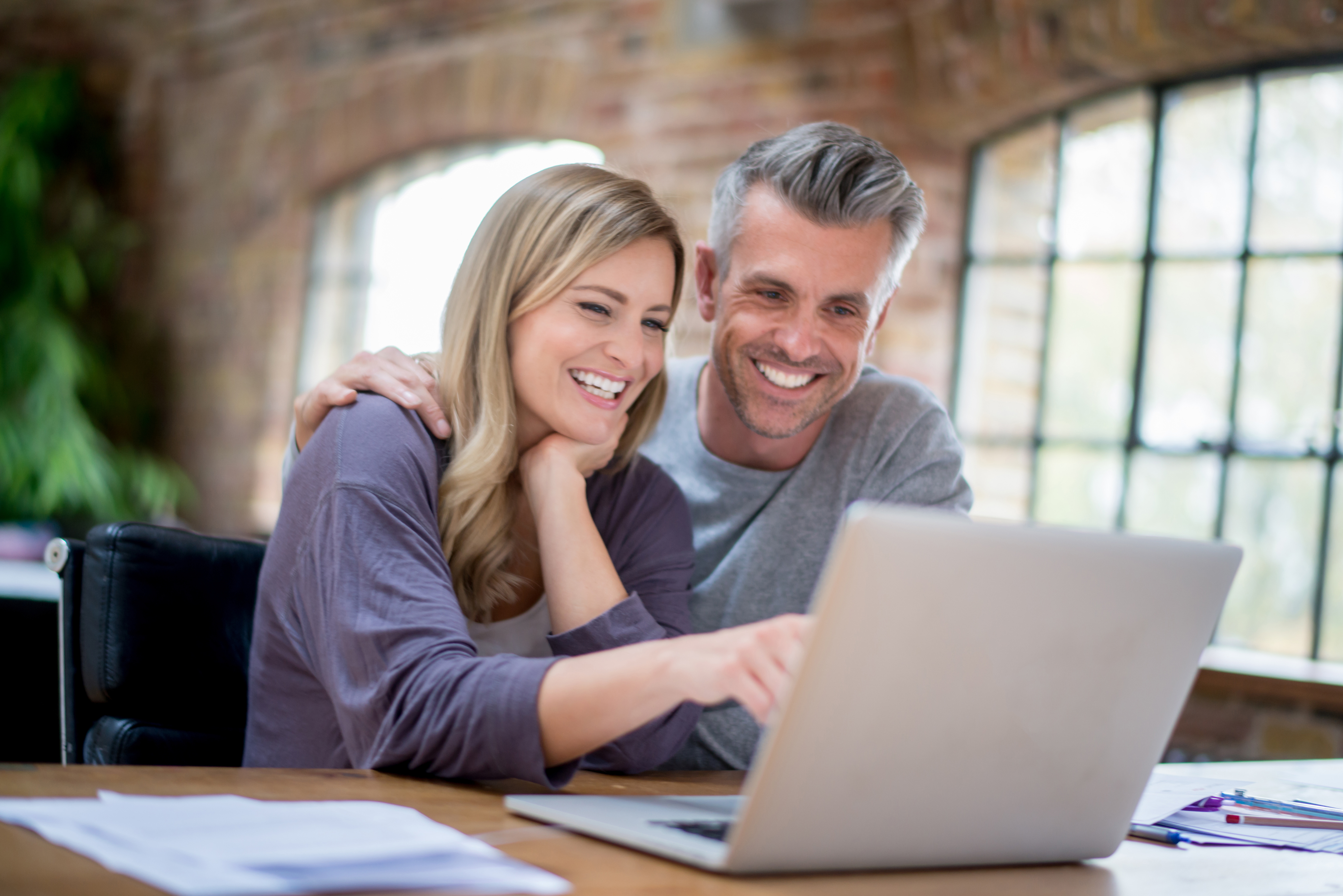 Couple souriant consultant leurs finances sur un ordinateur